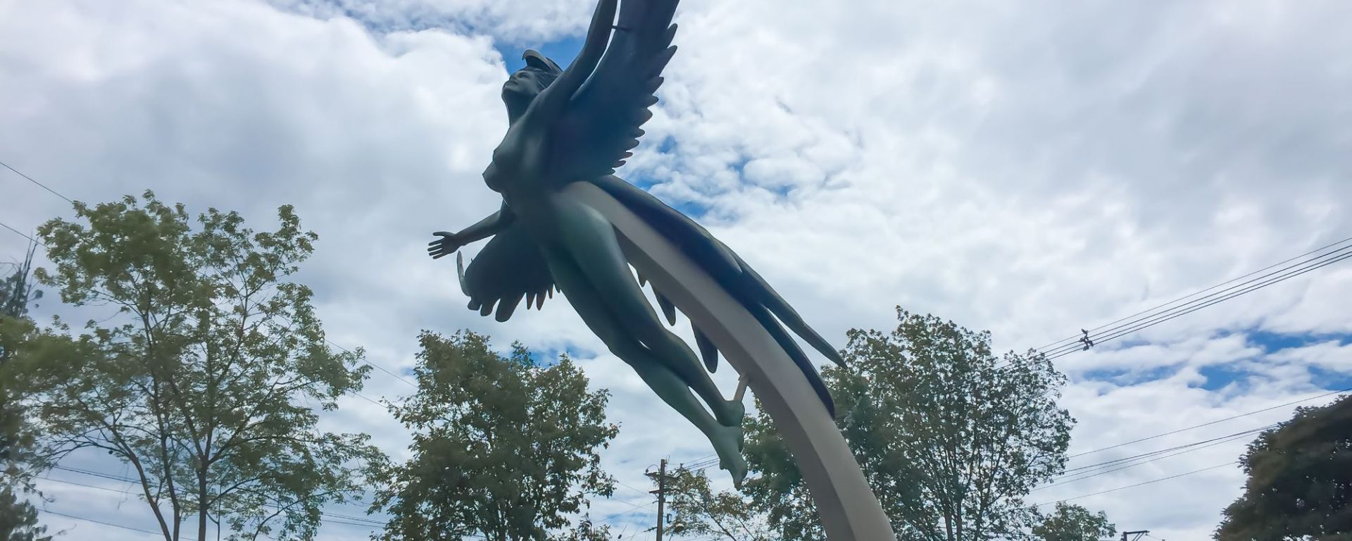 A large sculpture of a winged female with arms and wings wide open attached to a outstretched platform located at a roundabout entering El Penol- guatape