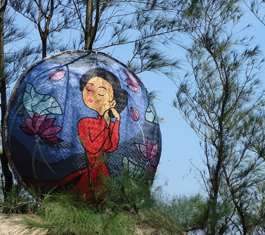 A painting of a Vietnamese women wearing a red dresspainted basket boat at Tam Thanh Mural Village